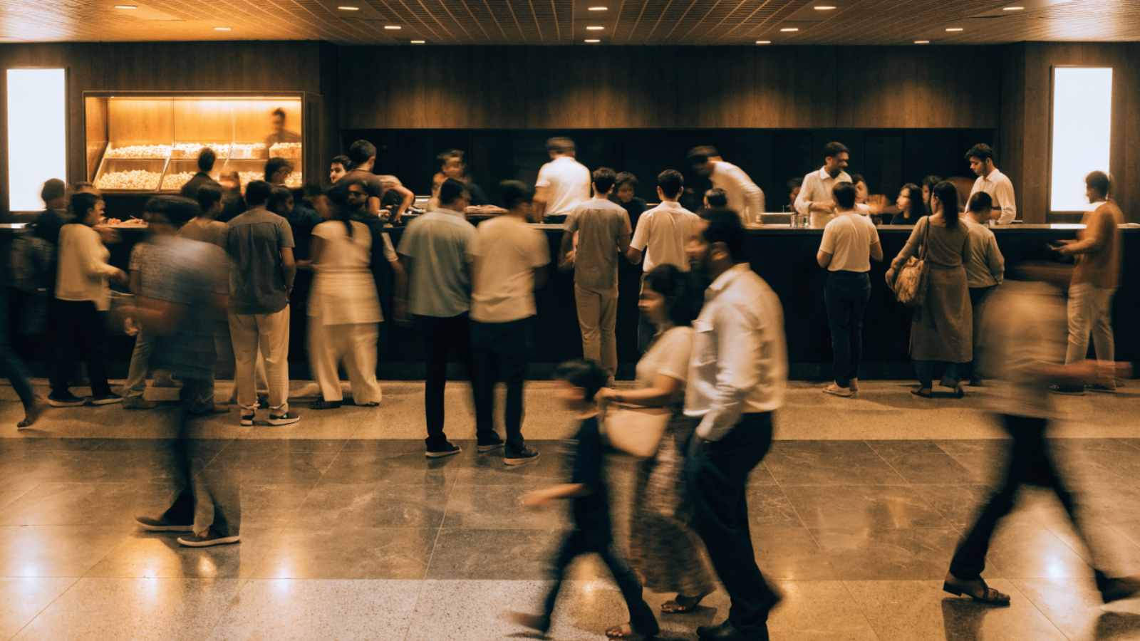 Crowds at the counter of a busy Indian multiplex lobby with a concession stand behind