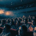 Hundreds of faces lit by the projector beam in a full Indian single-screen cinema
