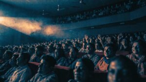Hundreds of faces lit by the projector beam in a full Indian single-screen cinema
