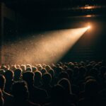 A packed cinema auditorium lit by the projector beam