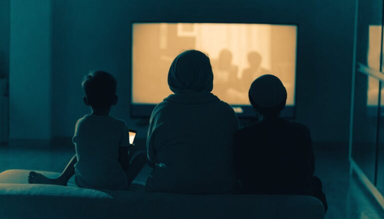 A family watching a glowing screen at home at night