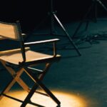 An empty director's chair in a spotlight on a dark set