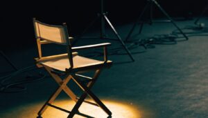 An empty director's chair in a spotlight on a dark set
