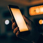 A glowing phone held in the dark against cinema lights