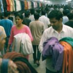 Shoppers pushing through dense racks of clothing in a busy Indian value-fashion store