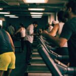 Men and women training on treadmills and free weights in a crowded Indian budget gym