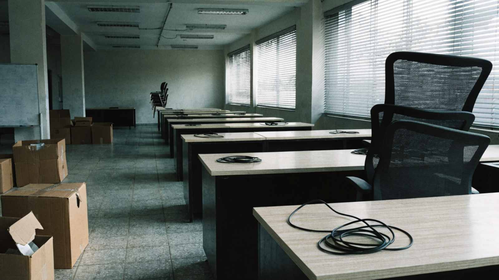 Rows of desks with coiled cables and no computers in a vacated Indian office