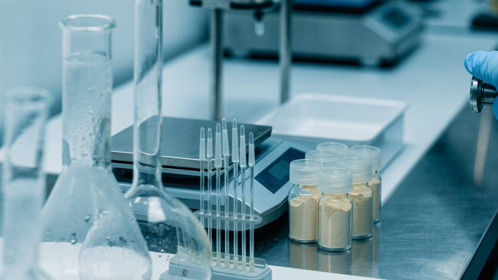 Glassware, an analytical balance and powder sample vials on a laboratory bench