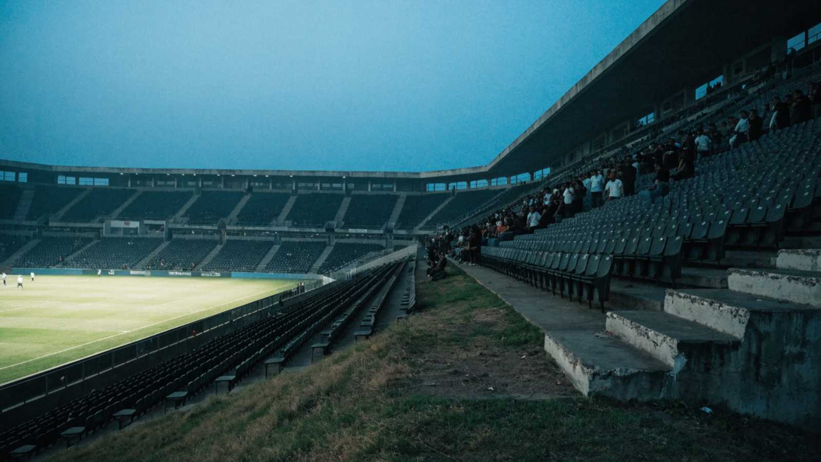 Blocks of empty seats and a scattered pocket of supporters at an Indian league match