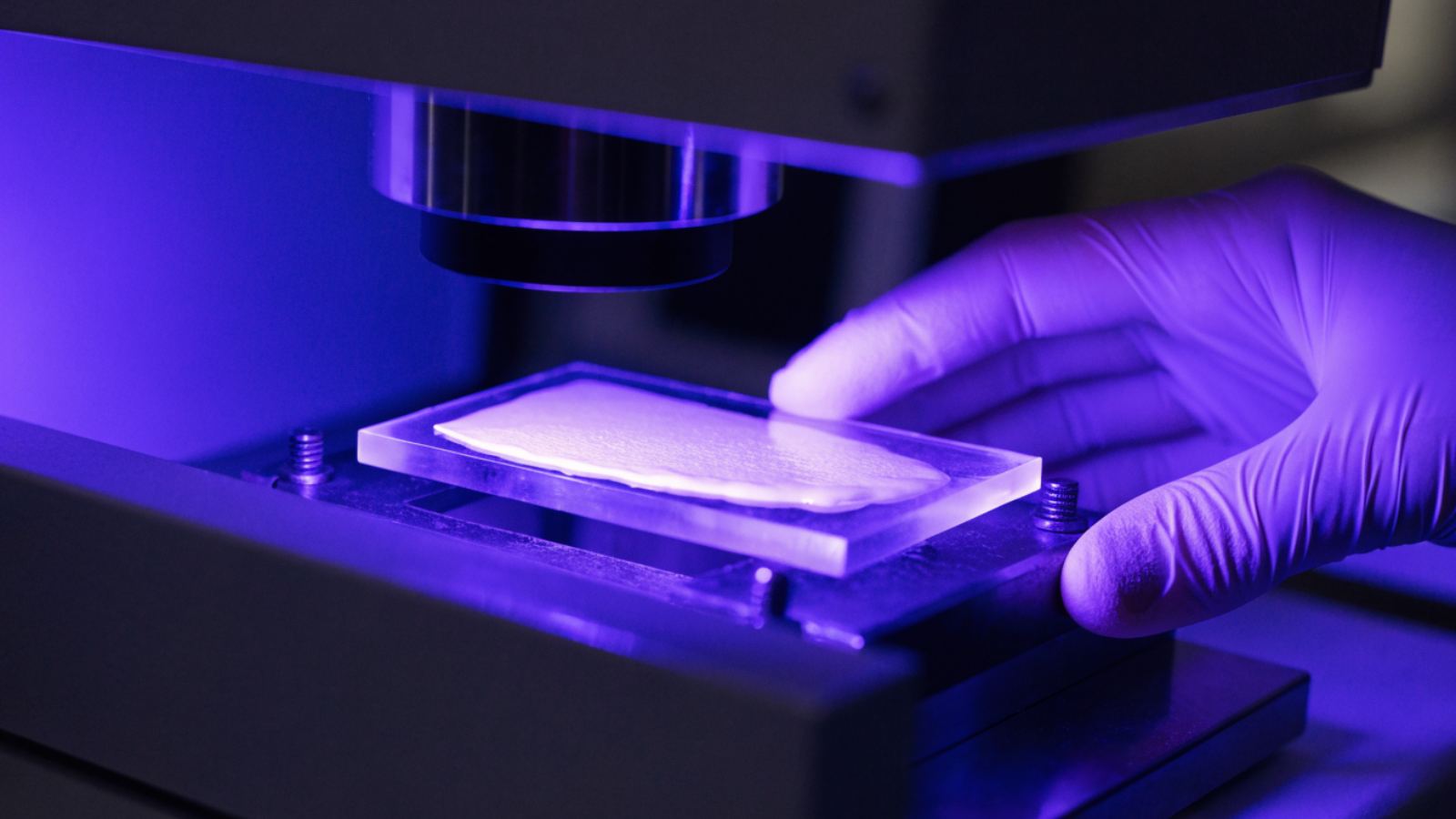 A cream film on a quartz plate under a violet UV lamp in a testing instrument